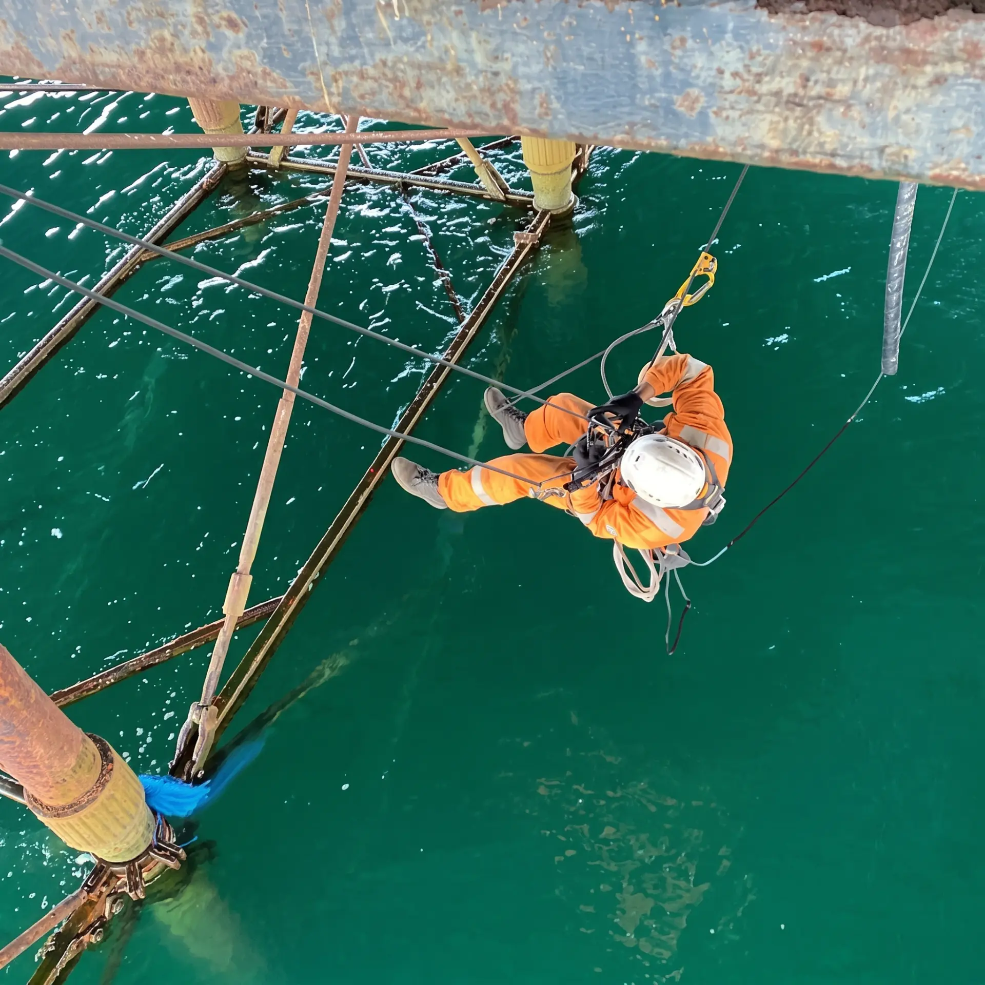 Rope access operative suspended beneath a steel structure over water