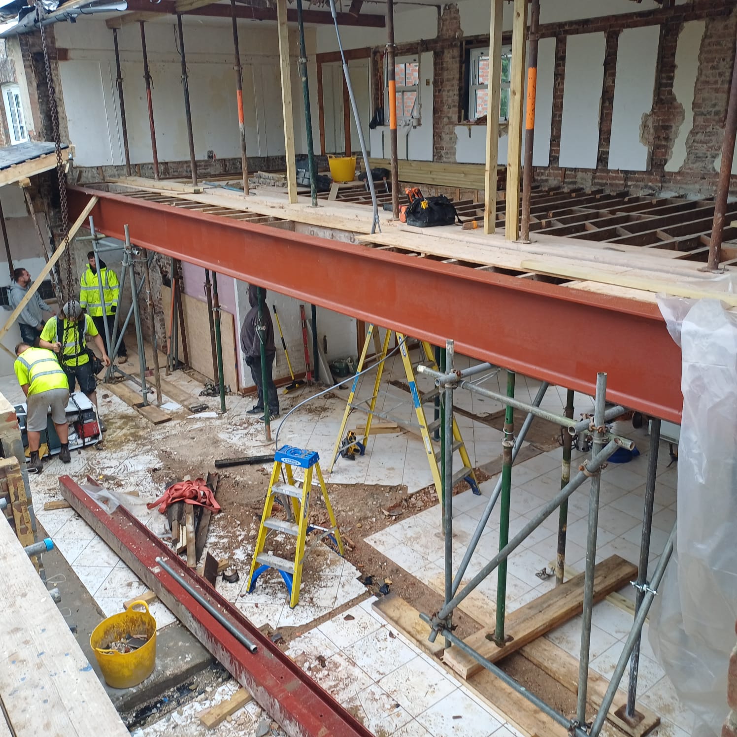 Long steel beam installed on props during a structural opening