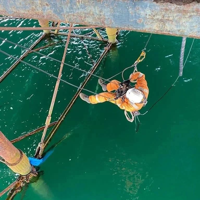 Rope access operative working on offshore steel pier structure